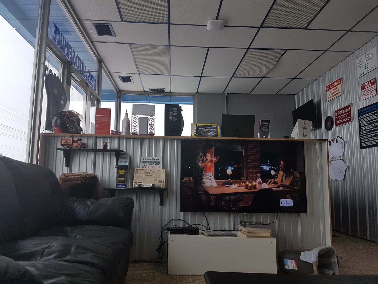 The Ness Auto Service waiting room with a couch, a wall TV and a counter of memorabilia