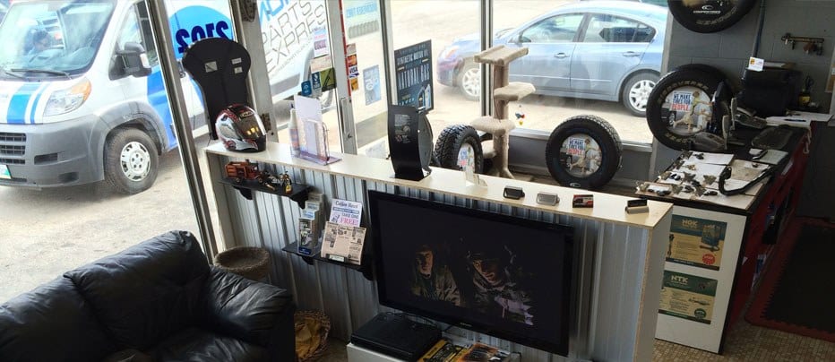 The waiting area: a leather couch, a wall TV and a tire display by the front window